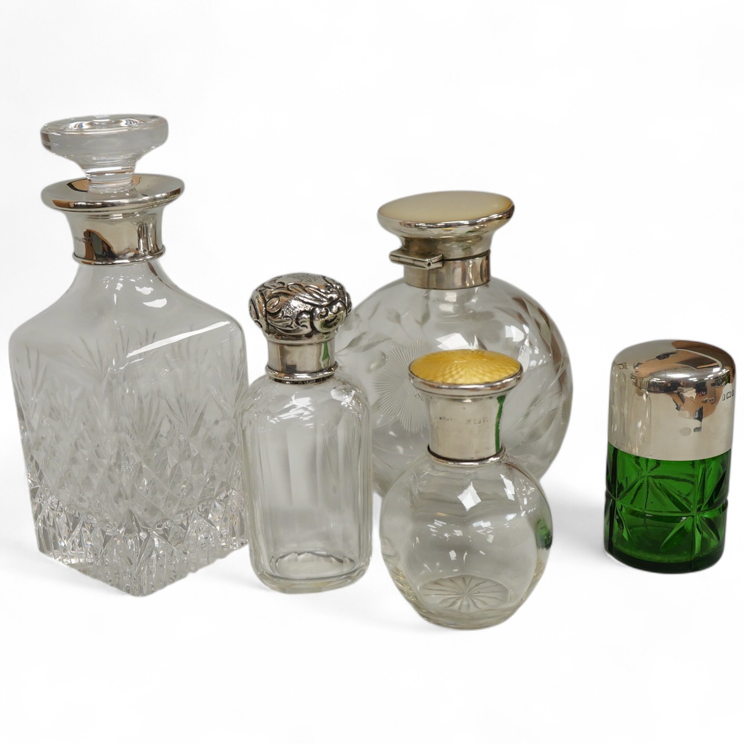 A collection of five silver mounted glass scent bottles to include one with guilloche enamel inset top, a Victorian example hallmarked for Chester 1897 and a cut glass example with mother of pearl top, London 1922, large
